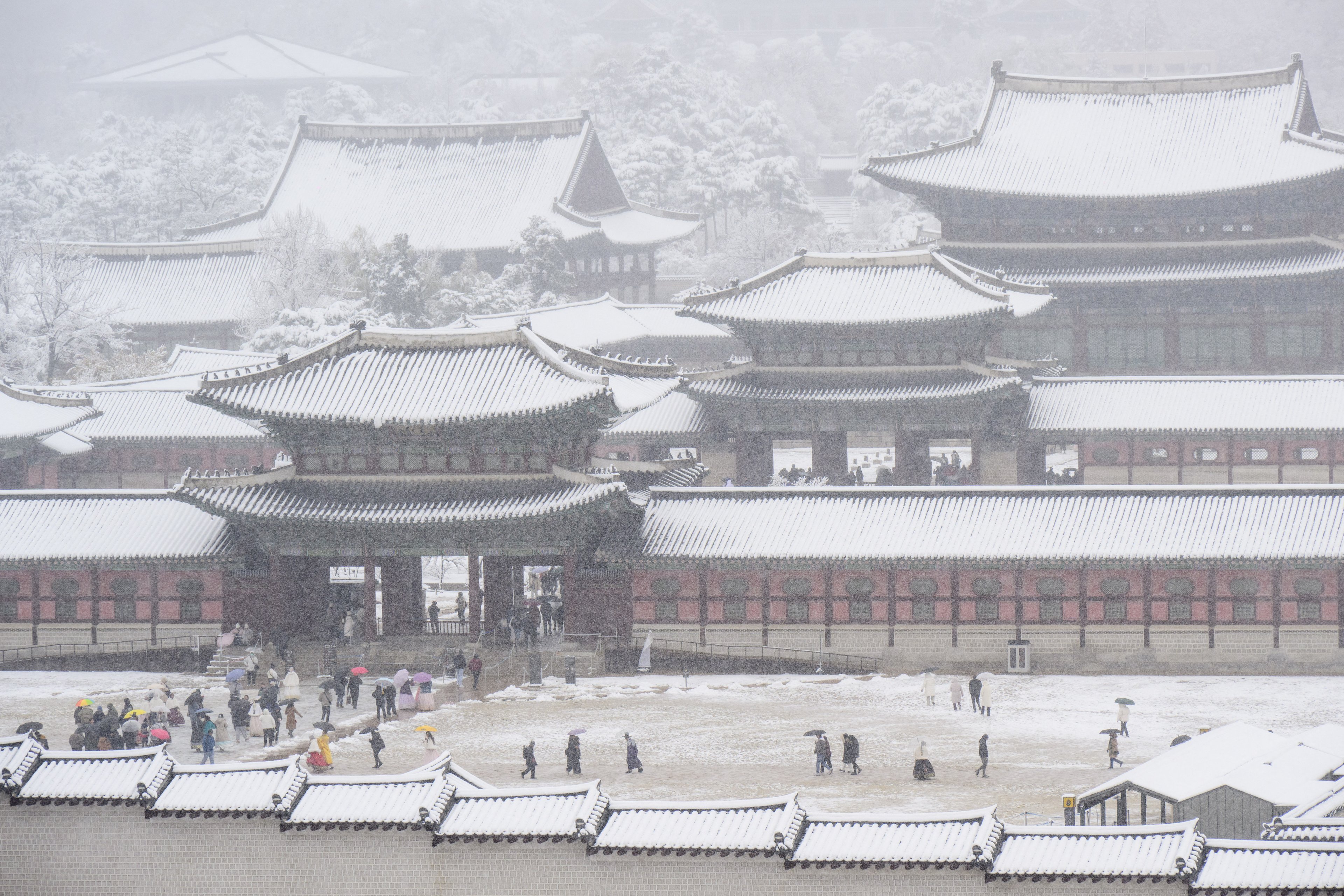 Pessoas visitam o Palácio Gyeongbokgung em meio a uma forte nevasca no centro de Seul em 27 de novembro de 2024. A capital da Coreia do Sul foi coberta em 27 de novembro pela maior nevasca de novembro desde que os registros começaram há mais de um século, disse a agência meteorológica