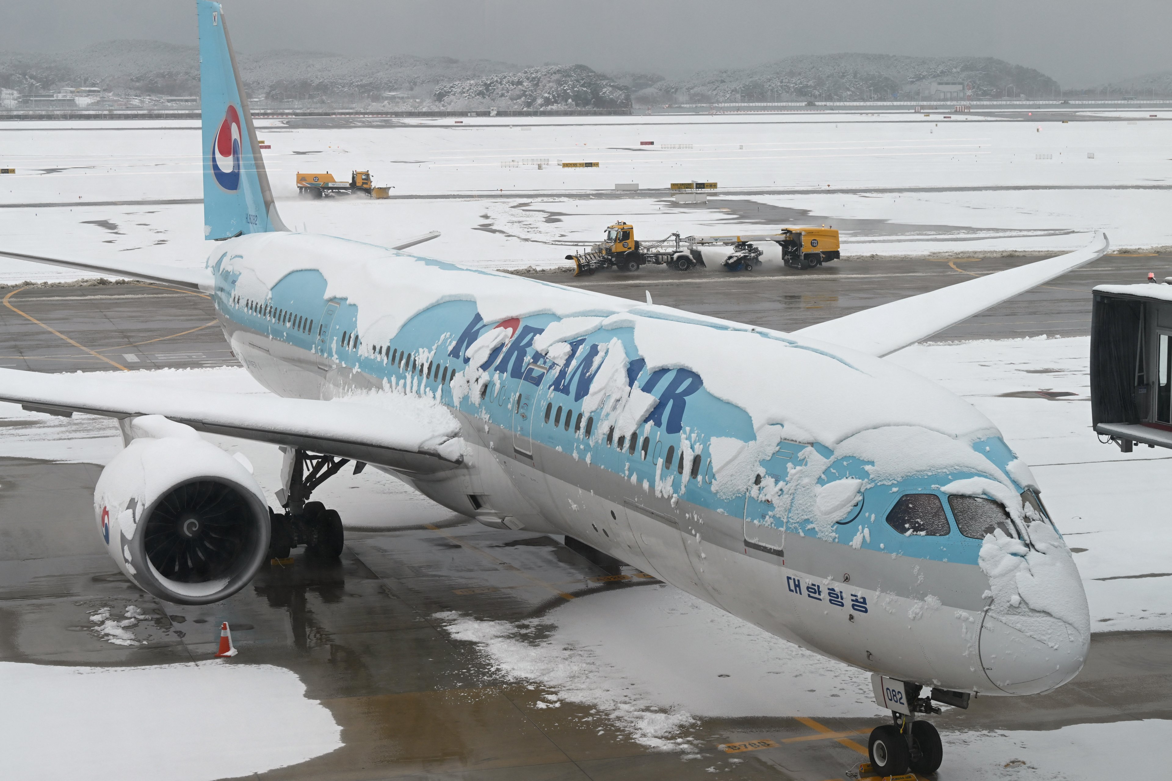 Um avião da Korean Air está estacionado na pista durante a queda de neve, visto através de uma janela no aeroporto internacional de Incheon, a oeste de Chocks