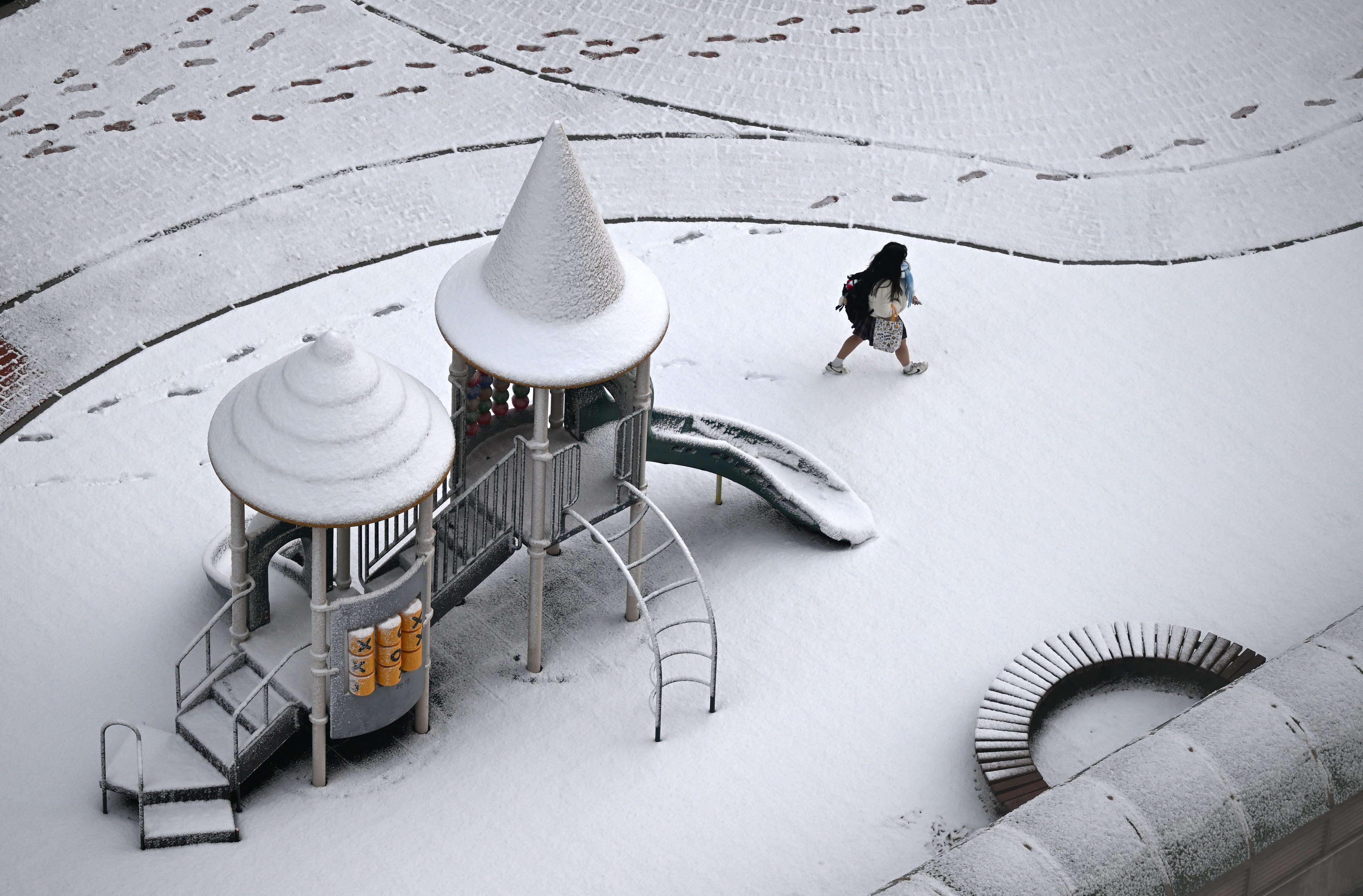 Um estudante caminha por um playground coberto de neve após uma nevasca em Goyang em 27 de novembro de 2024