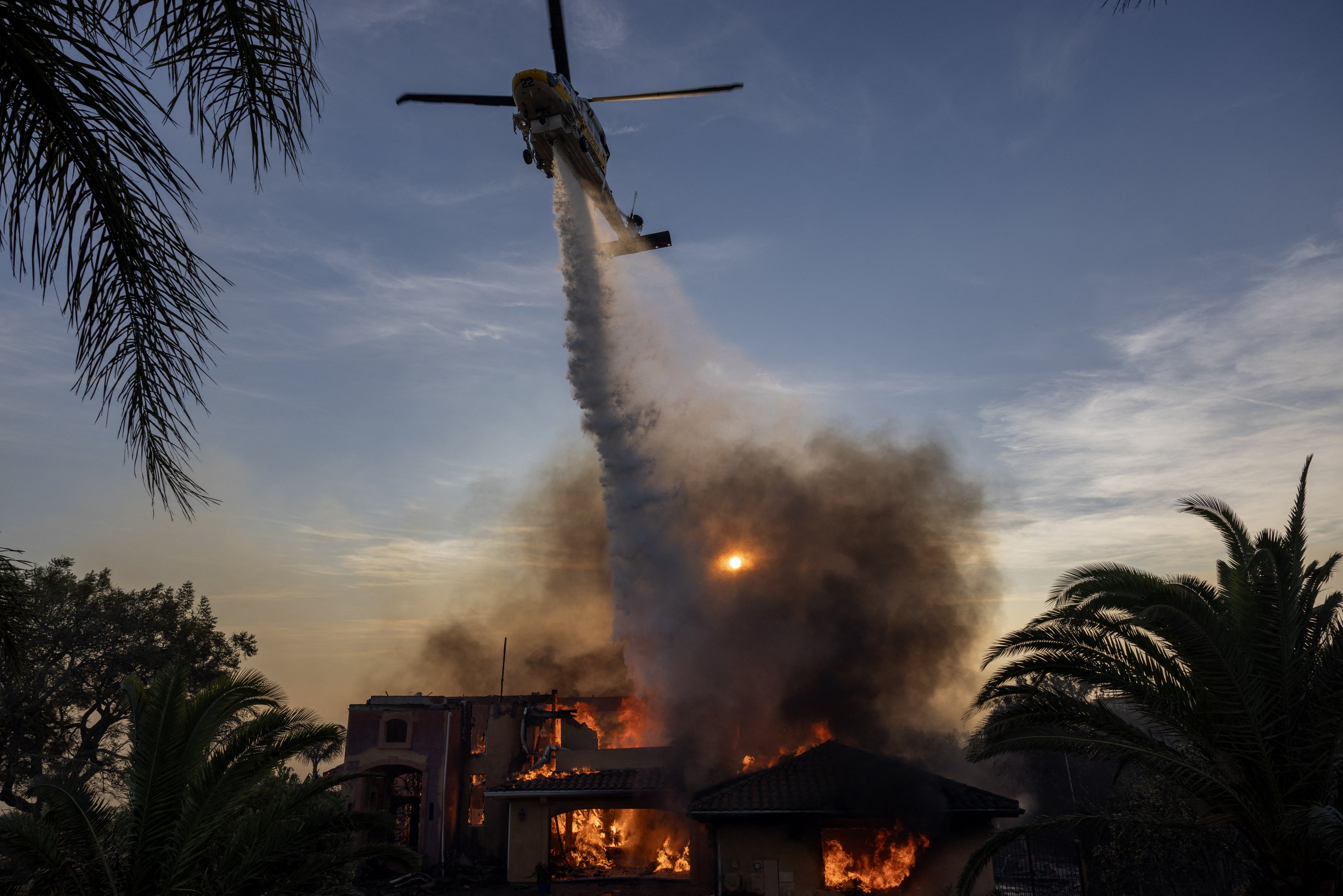 CAMARILLO, CALIFÓRNIA - 6 DE NOVEMBRO: Um helicóptero joga retardante de fogo enquanto uma casa queima no Mountain Fire em 6 de novembro de 2024 em Camarillo, Califórnia. Impulsionado por ventos fortes, o fogo queimou mais de 10.000 acres desde que começou esta manhã