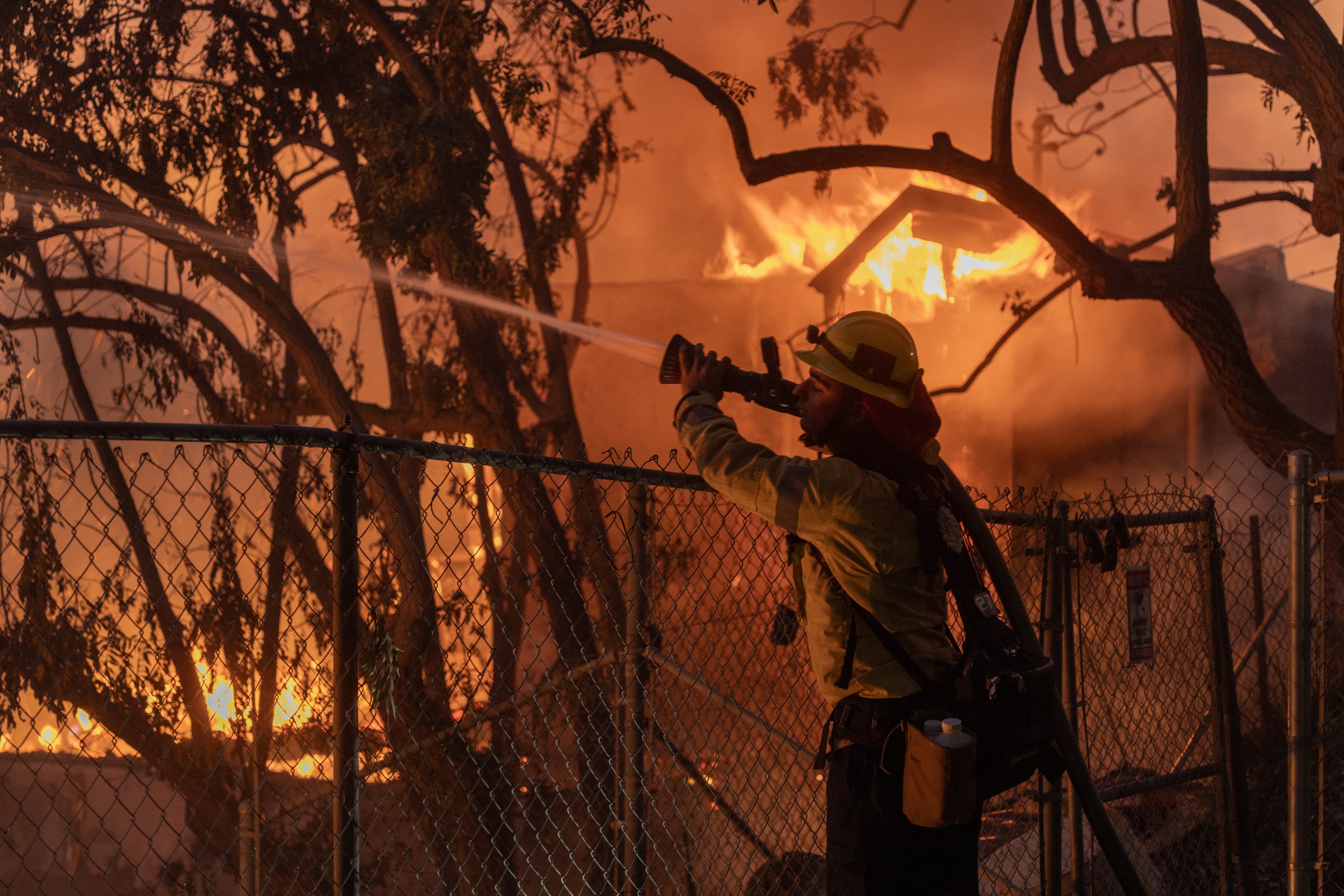 Um bombeiro do Condado de Los Angeles luta contra as chamas enquanto uma casa queima no Mountain Fire em 6 de novembro de 2024 em Camarillo, Califórnia. Impulsionado por ventos fortes, o fogo queimou mais de 10.000 acres desde que começou esta manhã