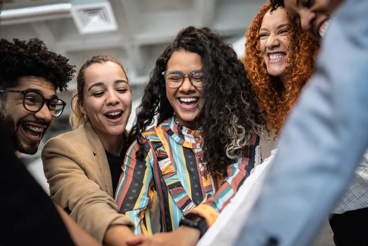 Coworkers with stacked hands at the office (FG Trade/Getty Images)