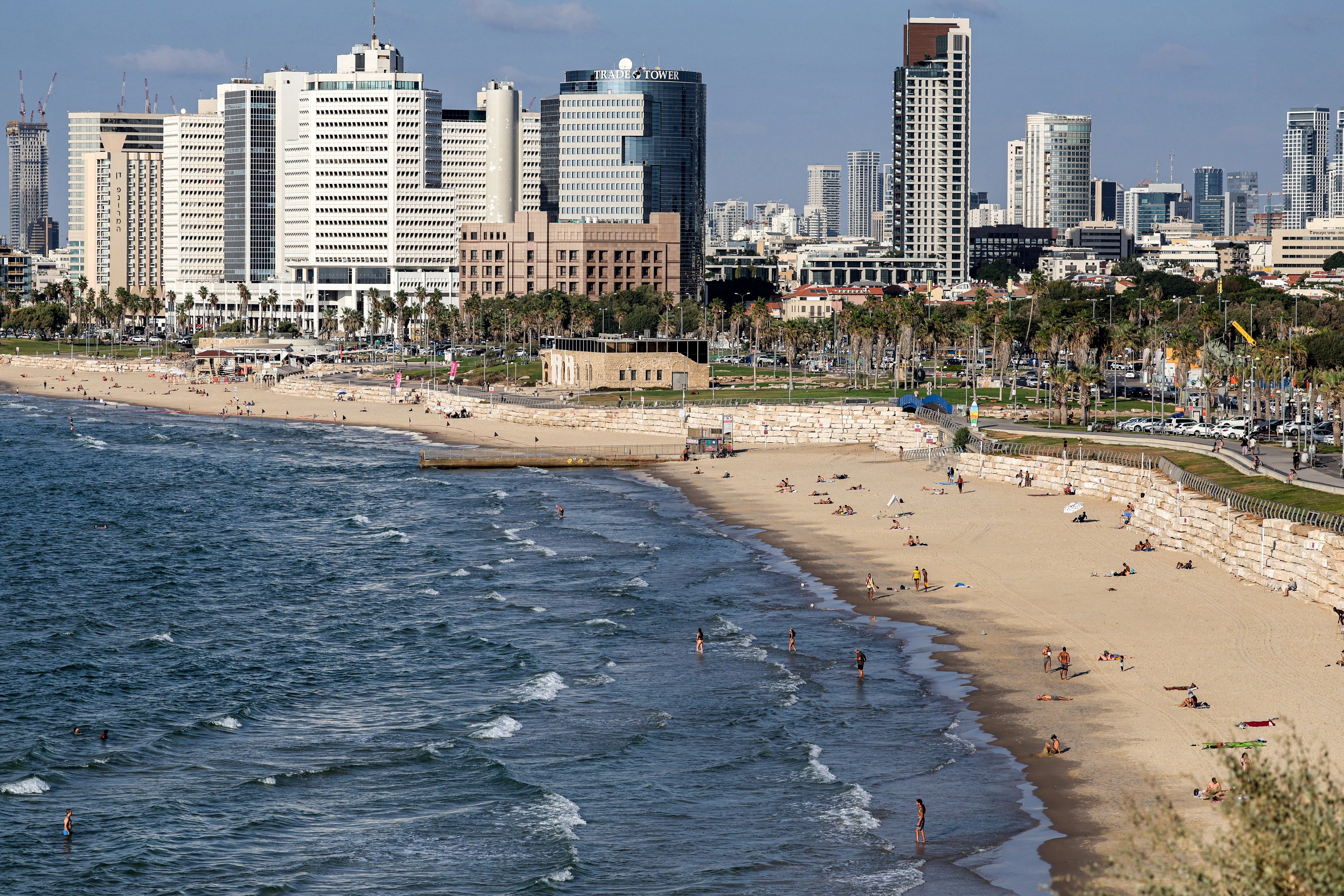 This overview taken from Jaffa shows beachgoers sunbathing and wading in the Mediterranean sea waters along a beach before high-rise buildings along the waterfront in Israel's central coastal city of Tel Aviv on October 10, 2024. (Photo by Ahmad GHARABLI / AFP) (Photo by AHMAD GHARABLI/AFP via Getty Images)