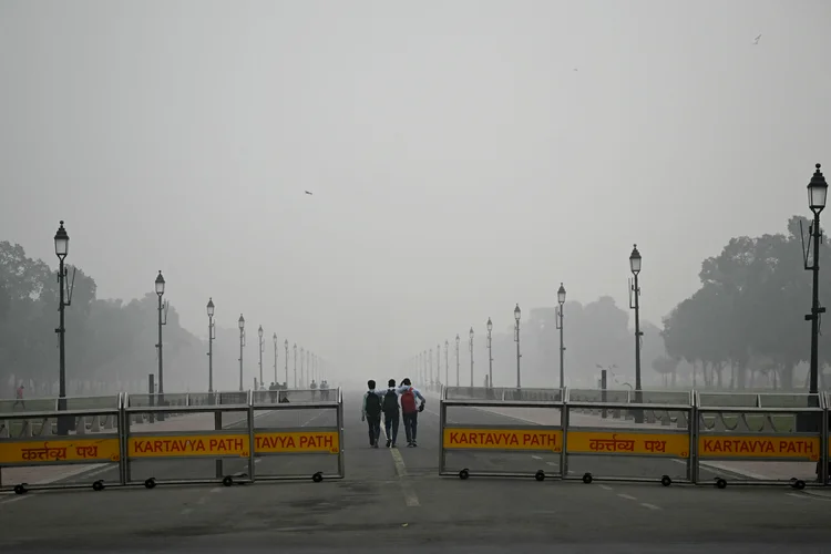 Pessoas caminham ao longo do Caminho Kartavya perto do Portão da Índia envoltos em poluição em Nova Déli em 13 de novembro de 2024 (Money SHARMA / AFP/Getty Images)