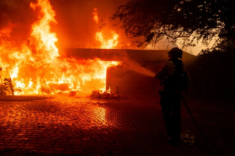 Bombeiro tenta controlar o fogo que consome uma casa em Camarillo, Califórnia, em 6 de novembro de 2024 (AFP)