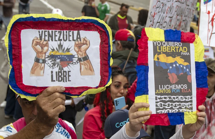 Manifestantes seguram cartazes contra o governo do presidente venezuelano Nicolás Maduro durante um comício em Bogotá, 1º de dezembro de 2024 (Alejandro Martinez/AFP)