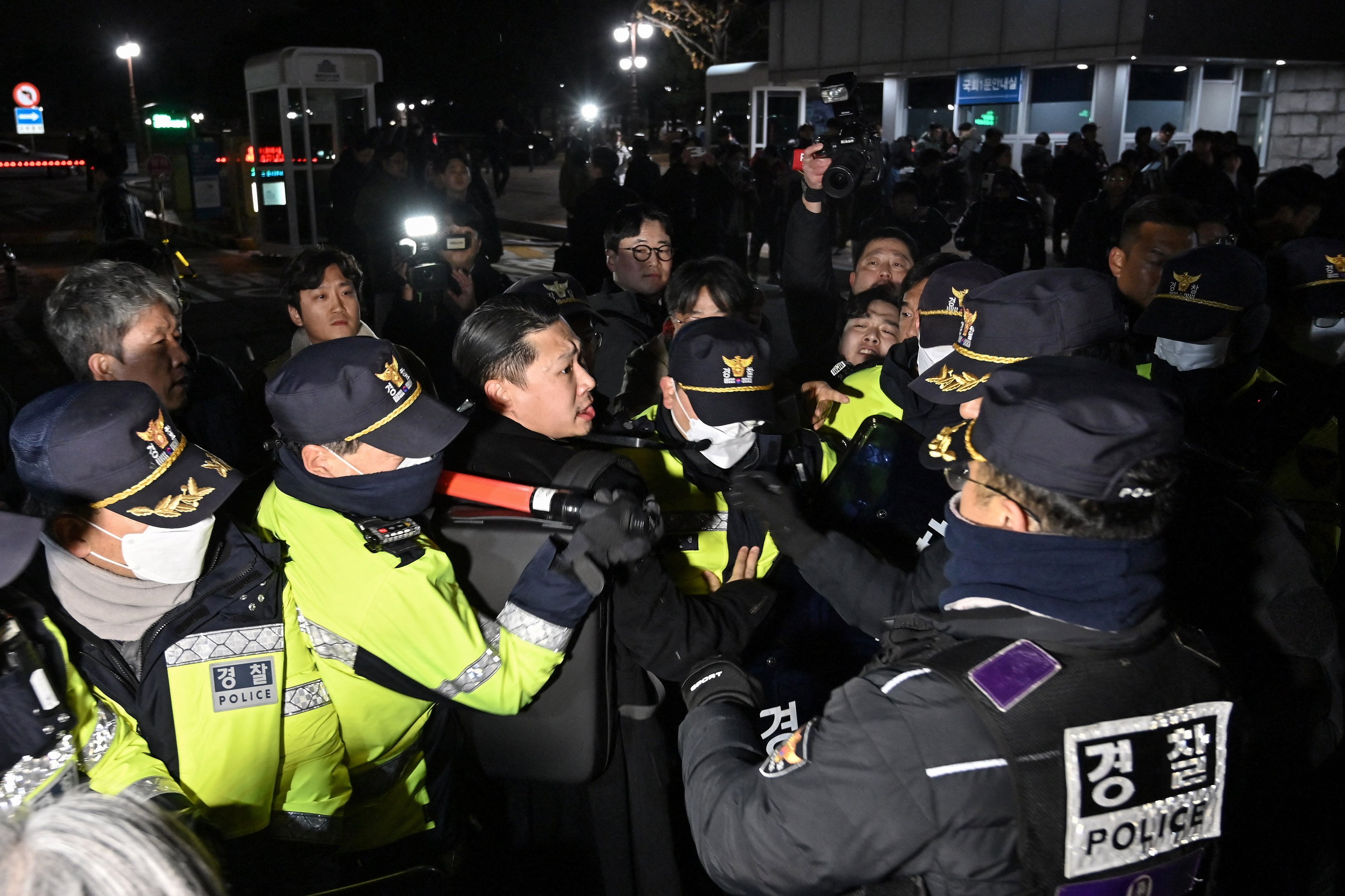 A polícia tenta conter pessoas que tentam entrar na Assembleia Nacional em frente ao portão principal da Assembleia Nacional em Seul, Coreia do Sul, em 3 de dezembro de 2024, depois que o presidente Yoon Suk Yeol declarou lei marcial de emergência. O presidente da Coreia do Sul, Yoon Suk Yeol, declarou lei marcial de emergência em 3 de dezembro, dizendo que a medida era necessária para proteger o país de "forças comunistas" em meio a disputas parlamentares sobre um projeto de lei orçamentária