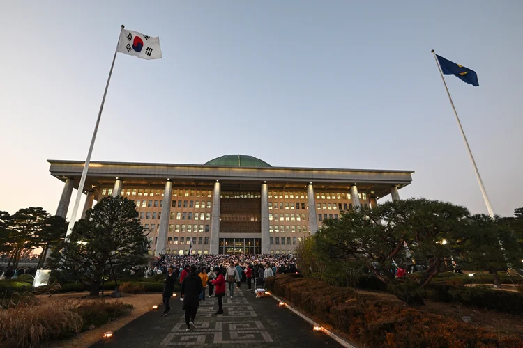 Manifestantes participam de um comício à luz de velas pedindo a deposição do presidente da Coreia do Sul, Yoon Suk Yeol, nos degraus da Assembleia Nacional em Seul, em 5 de dezembro de 2024. Yoon ainda estava agarrado ao poder em 5 de dezembro, com seu partido anunciando que se oporia a uma moção de impeachment após sua curta imposição da lei marcial ter surpreendido o mundo ( JUNG Yeon-je /AFP)