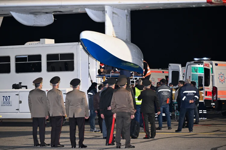 Funcionários de terra e médicos do aeroporto auxiliam cidadãos azerbaijanos, que sobreviveram à queda do jato de passageiros Embraer 190 da Azerbaijan Airlines perto da cidade de Aktau, no oeste do Cazaquistão, ao chegarem ao Aeroporto Internacional Heydar Aliyev, em Baku, em 26 de dezembro de 2024. (STRINGER/AFP)