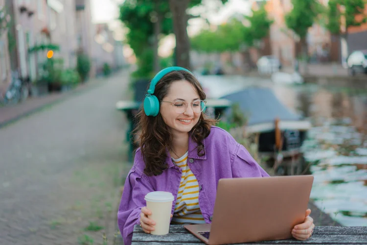 Young Caucasian sitting at the outdoor table, working with laptop and drinking coffee (Oleh_Slobodeniuk/Getty Images)