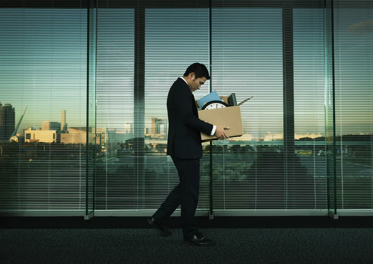 Subject: A Japanese business office worker leaving his job with all his belonging in a layoff and economic recession. (YinYang/Getty Images)