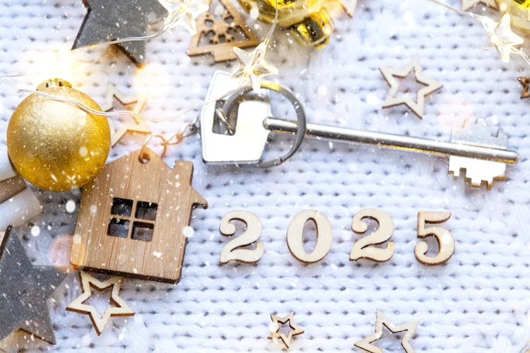 House key with keychain cottage on festive background with stars, lights of garlands. New Year 2025 wooden letters, greeting card. Purchase, construction, relocation, mortgage, insurance (Reprodução)