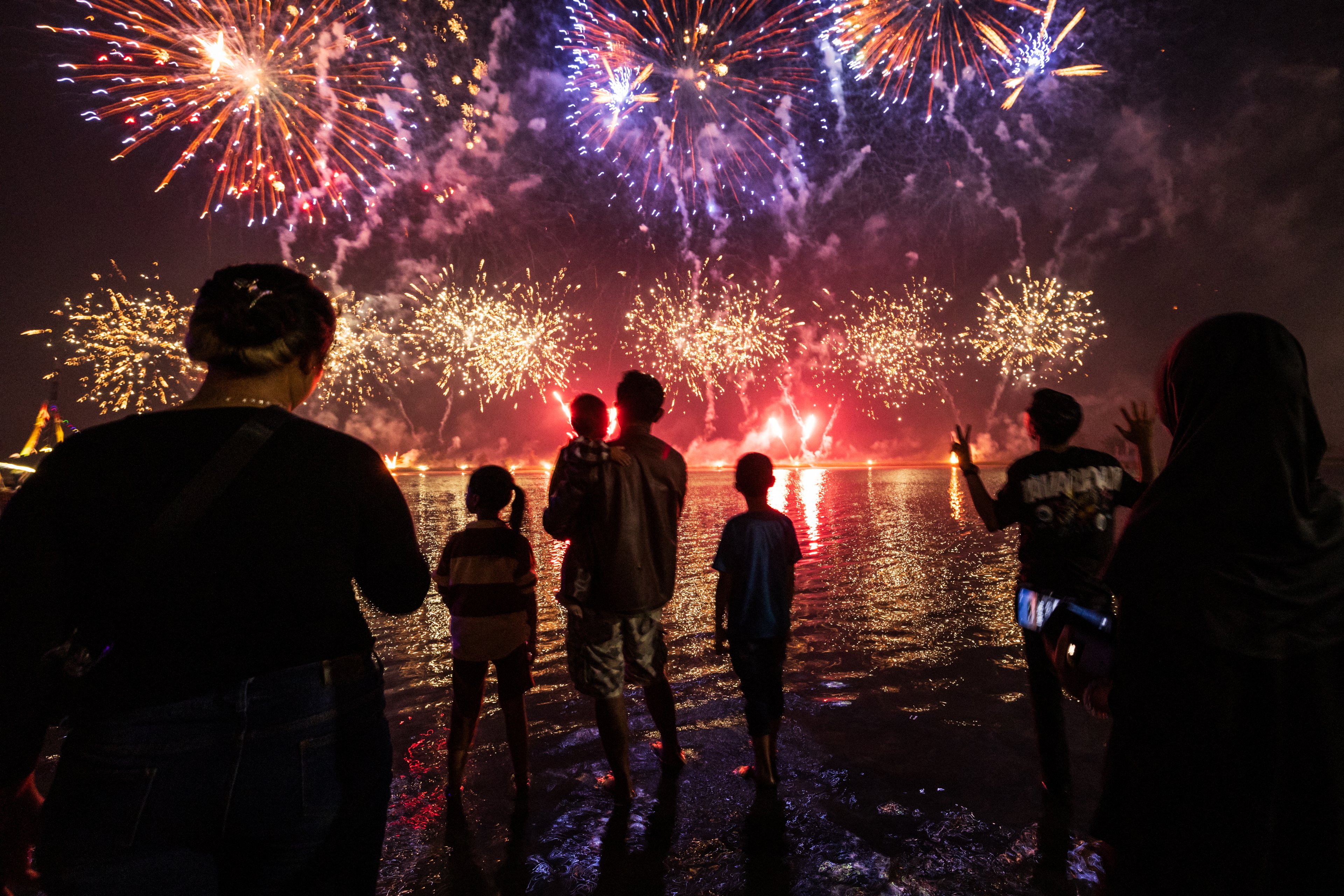 Local residents look at fireworks as they celebrate the New Year at Ancol Beach in Jakarta on January 1, 2025. (Photo by  / AFP)