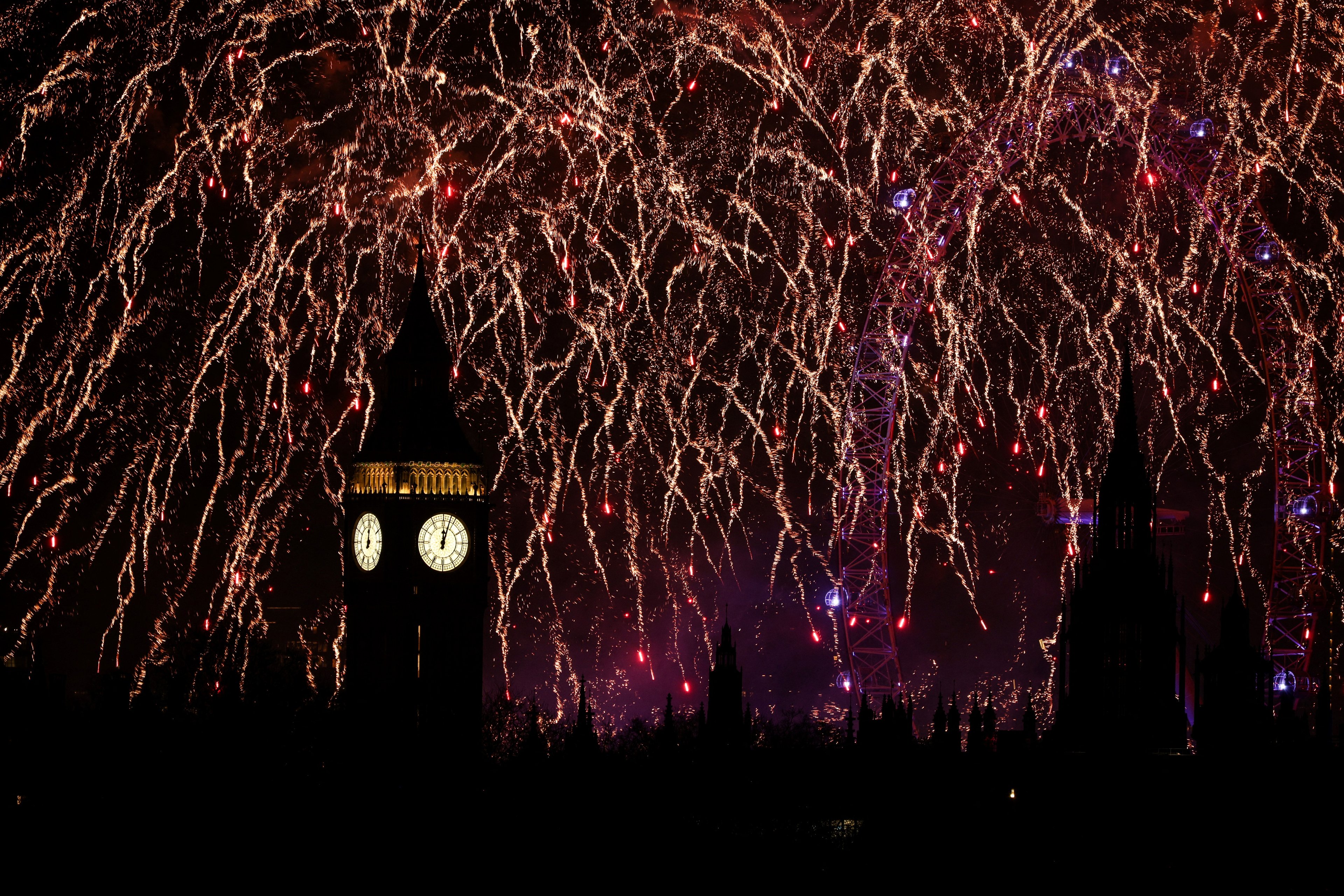 Fireworks explode in the sky around the London Eye and The Elizabeth Tower, commonly known by the name of the clock's bell, "Big Ben", at the Palace of Westminster, home to the Houses of Parliament, in central London, just after midnight on January 1, 2025. (Photo by  / AFP)