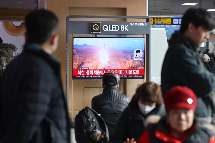 Pessoas assistem a uma televisão mostrando um noticiário com imagens de arquivo de um teste de míssil norte-coreano, em uma estação ferroviária em Seul em 6 de janeiro de 2025 (Anthony WALLACE/AFP)