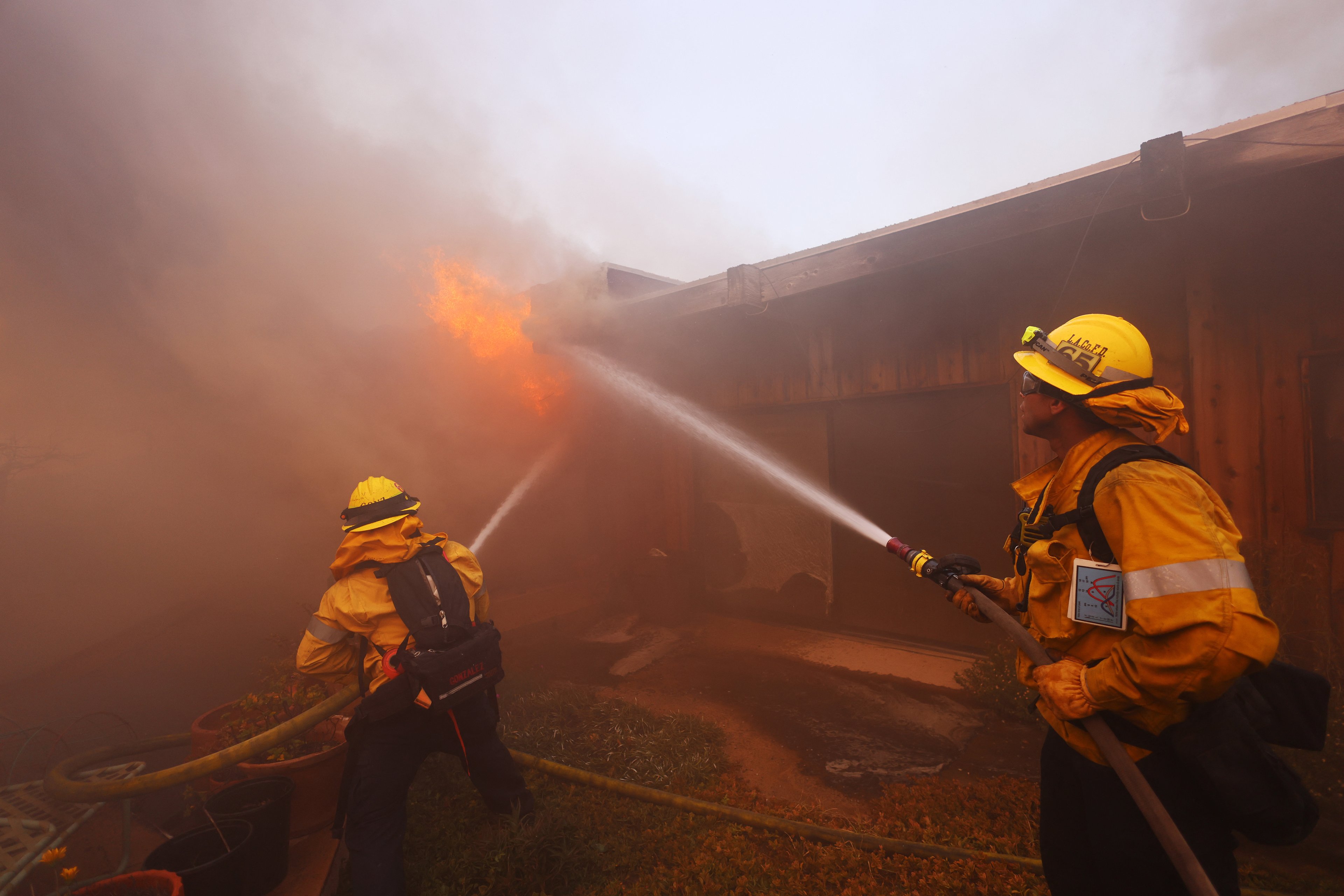 Bombeiros trabalham para extinguir chamas que engolfam uma casa enquanto um incêndio florestal assola Pacific Palisades, Califórnia, em 7 de janeiro de 2025. Um incêndio florestal de rápido avanço em um subúrbio de Los Angeles queimou prédios e provocou evacuações na terça-feira, enquanto ventos "com risco de morte" açoitavam a região. Mais de 200 acres (80 hectares) estavam queimando em Pacific Palisades, um local de luxo com casas multimilionárias nas Montanhas de Santa Monica, fechando uma rodovia importante e cobrindo a área com fumaça espessa