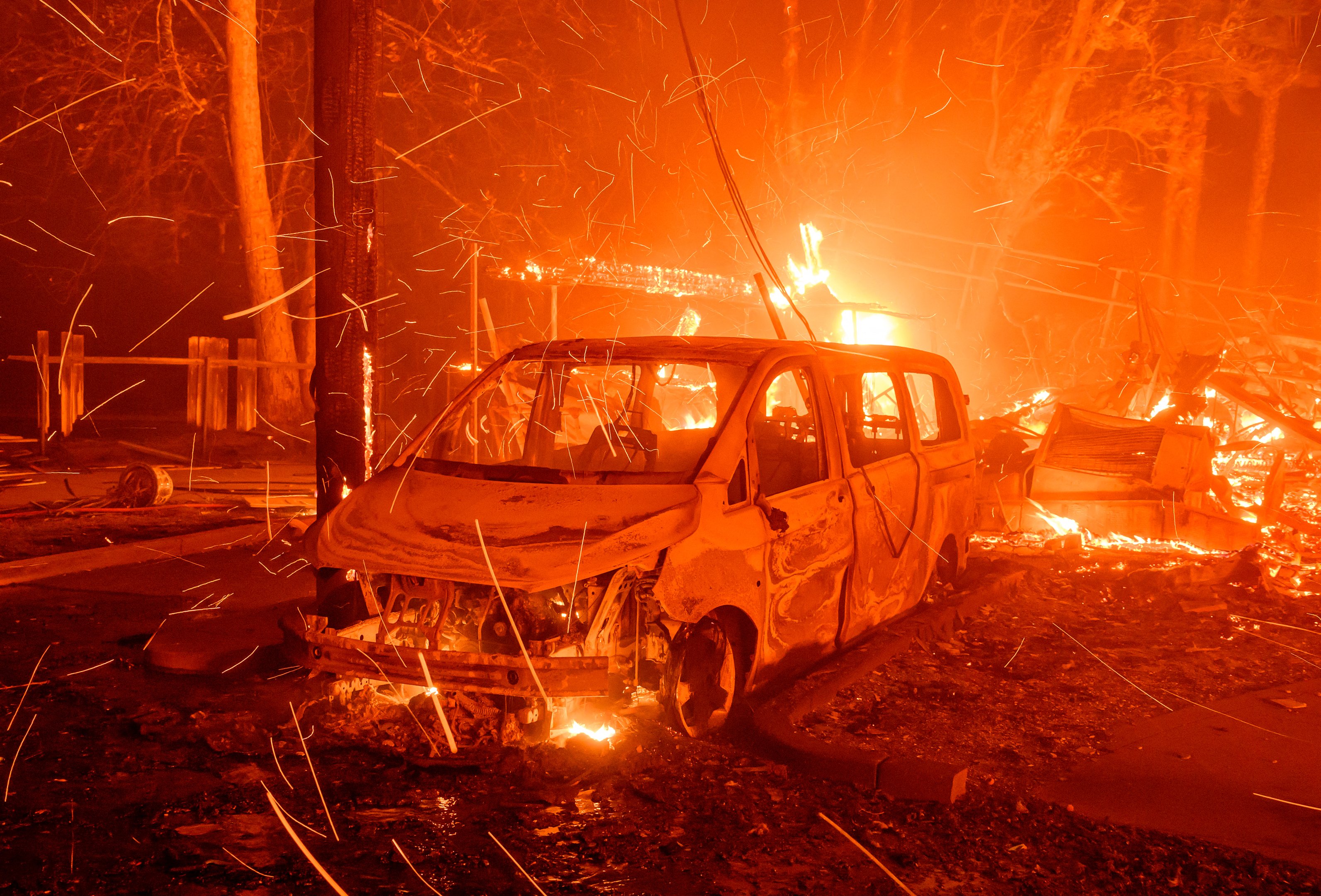 Brasas voam enquanto um veículo e uma propriedade queimam durante o incêndio de Eaton em Pasadena, Califórnia, em 8 de janeiro de 2025