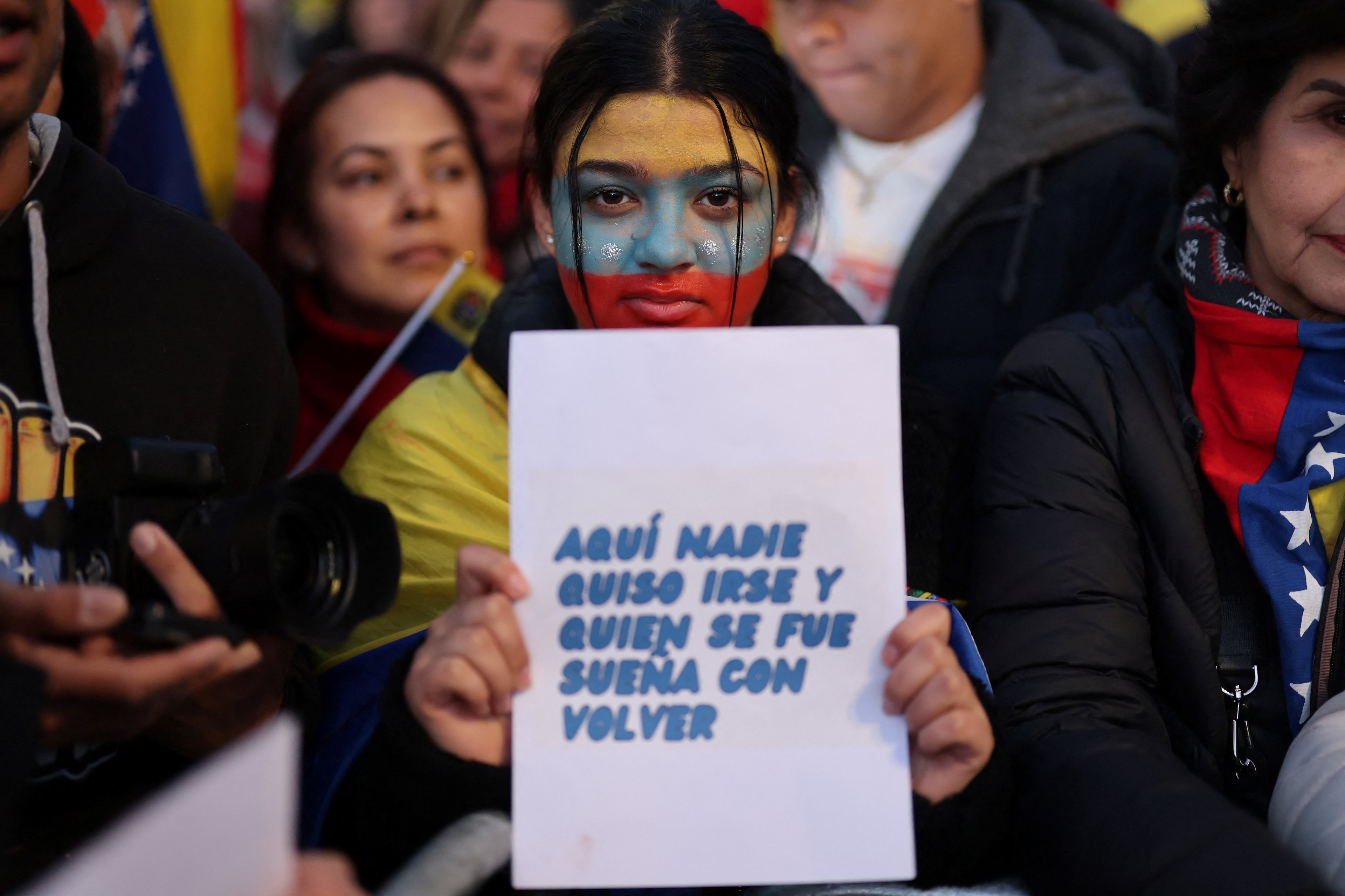 A protester holds a sign reading 'Nobody here wanted to leave, and everybody dreams to come back' in Madrid on January 9, 2025 during a demonstration for democracy in Venezuela, and in support of Venezuela's opposition candidate Edmundo Gonzalez, on the eve of the Venezuela's presidential inauguration. (Photo by Thomas COEX / AFP)