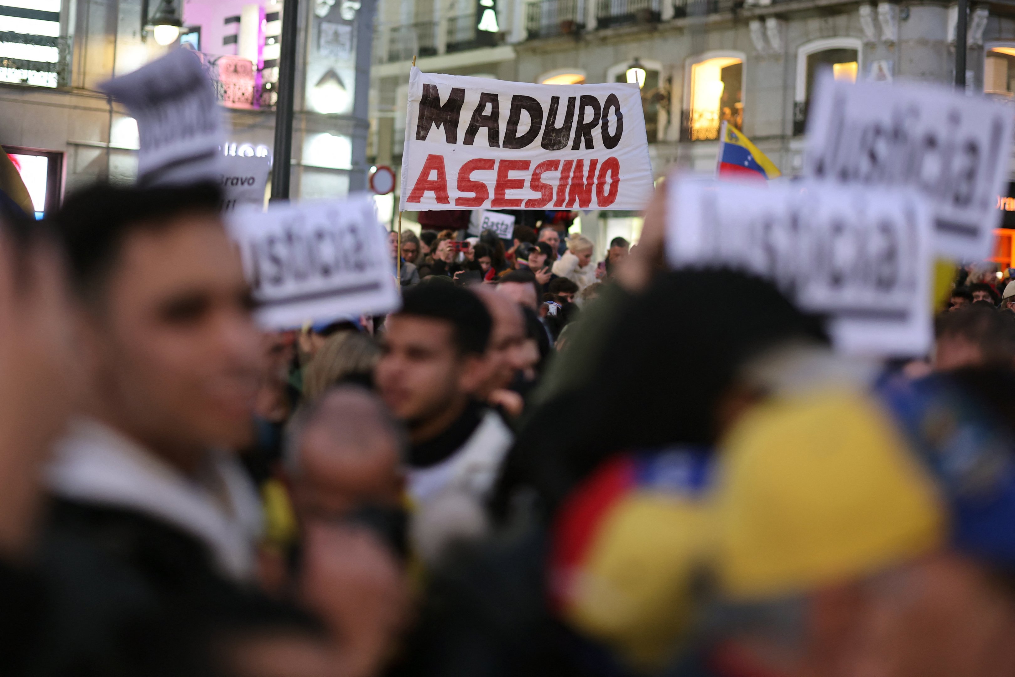 A protester holds a sign reading '(President) Maduro, murderer' in Madrid on January 9, 2025 during a demonstration for democracy in Venezuela, and in support of Venezuela's opposition candidate Edmundo Gonzalez, on the eve of the Venezuela's presidential inauguration. (Photo by Thomas COEX / AFP)