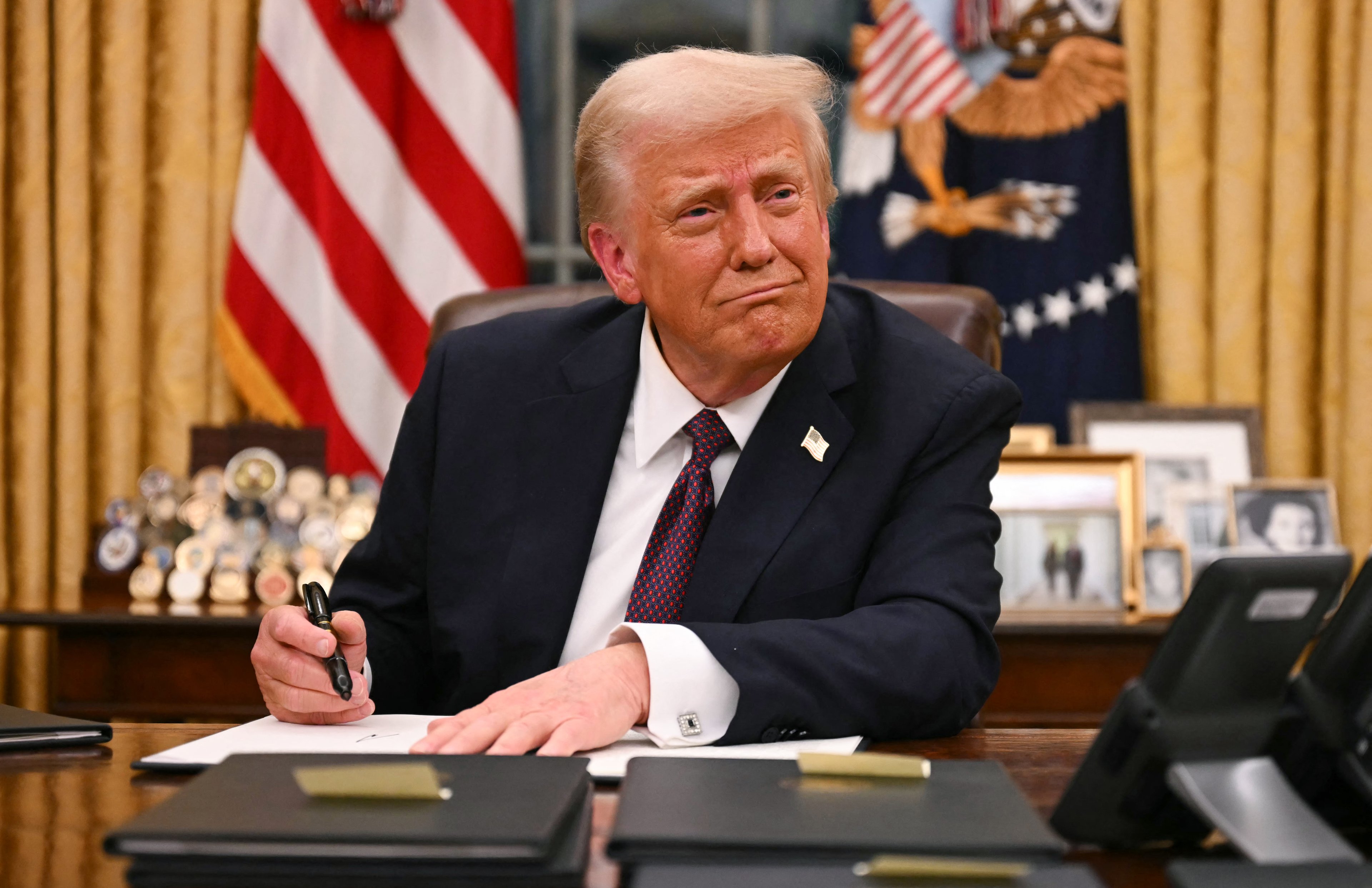 O presidente dos EUA, Donald Trump, assina ordens executivas no Salão Oval da Casa Branca em Washington, DC, em 20 de janeiro de 2025. (Foto de Jim WATSON / AFP)