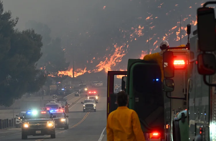 Bombeiros observam chamas do incêndio Hughes queimarem a encosta em Castaic, um bairro no noroeste do Condado de Los Angeles, Califórnia, em 22 de janeiro de 2025 (Robyn Beck/AFP)