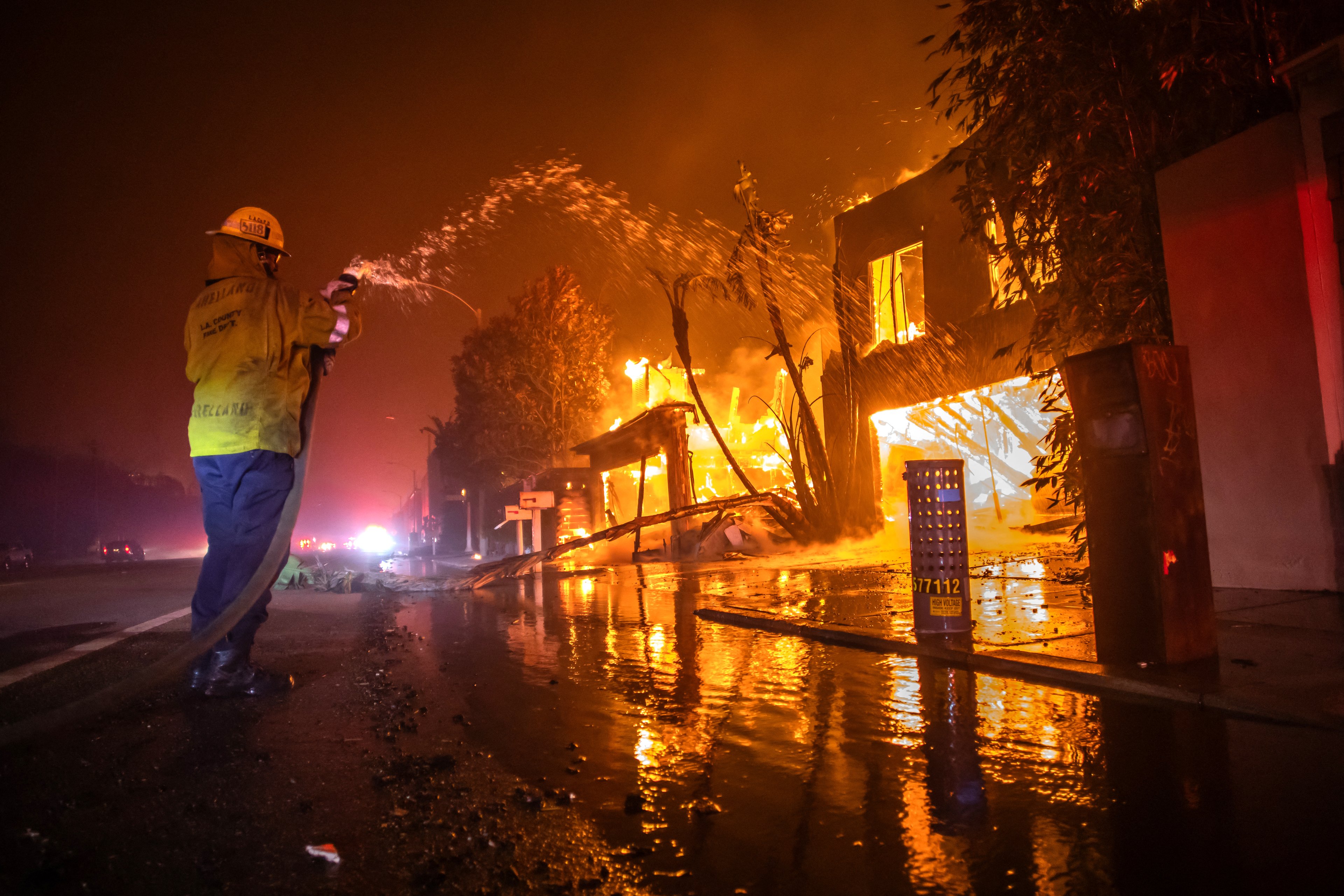 LOS ANGELES, CALIFORNIA - JANUARY 8: A firefighter battles the Palisades Fire while it burns homes at Pacific Coast Highway amid a powerful windstorm on January 8, 2025 in Los Angeles, California. The fast-moving wildfire has grown to more than 2900-acres and is threatening homes in the coastal neighborhood amid intense Santa Ana Winds and dry conditions in Southern California.   Apu Gomes/Getty Images/AFP (Photo by Apu Gomes / GETTY IMAGES NORTH AMERICA / Getty Images via AFP)