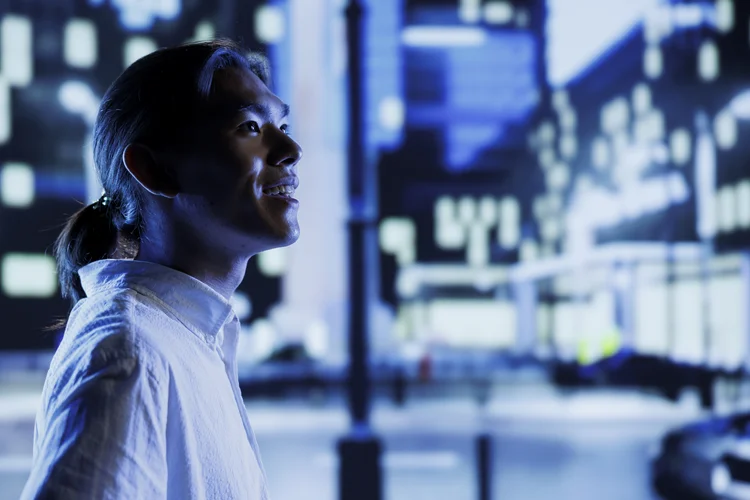 BIPOC man excited to wander around new city during nighttime, being amazed by nightlife environment buildings. Person visiting another town, walking around empty avenues at night