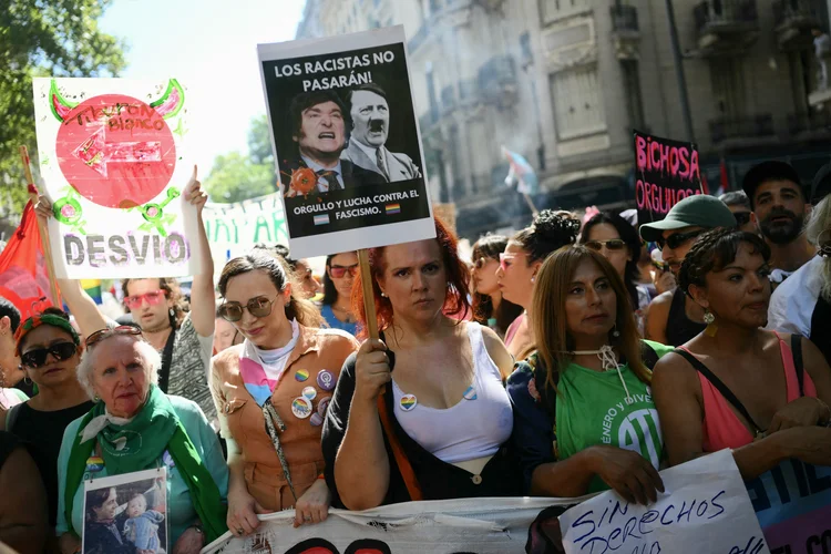 A demonstrator holds a sign with the images of Argentinian President and German Nazi leader Adolf Hitler that reads in spanish 'The racists will not pass' during a national march called by women and LGBTQ pride groups in repudiation of President Javier Milei's remarks in Davos on feminism and the LGBT community, in Buenos Aires on February 1st, 2025. Political, trade union and civil society sectors march against the advance of Milei's government on diversity policies. During his first year in office, Milei had dissolved the Ministry of Women, Gender and Diversity, as well as the National Institute Against Discrimination, Xenophobia and Racism. (Photo by Luis ROBAYO / AFP) (AFP Photo)