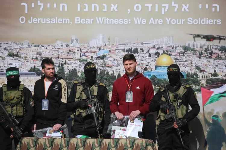 Sasha Trupanov e Sagui Dekel-Chen estão no palco ao lado de militantes palestinos durante a transferência (Eyad BABA / AFP)