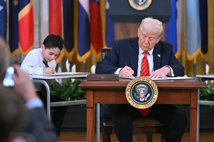 US President Donald Trump signs an executive order during an education event in the East Room of the White house in Washington, DC, March 20, 2025. President Donald Trump signed an order aimed at shutting down the Department of Education, a decades-long goal on the US right that objects to federal involvement in school systems run by individual states. By law, the Education Department -- created in 1979 -- cannot be shuttered without the approval of Congress, and Republicans do not have the votes to push that through. (Photo by ROBERTO SCHMIDT / AFP)