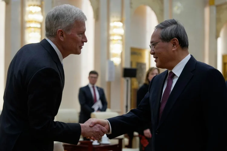 O primeiro-ministro da China, Li Qiang (D), cumprimenta o diretor-executivo da companhia Cargill, Brian Sikes, que faz parte de uma delegação liderada pelo senador americano Steve Daines, em Pequim, em 23 de março de 2025 (AFP)