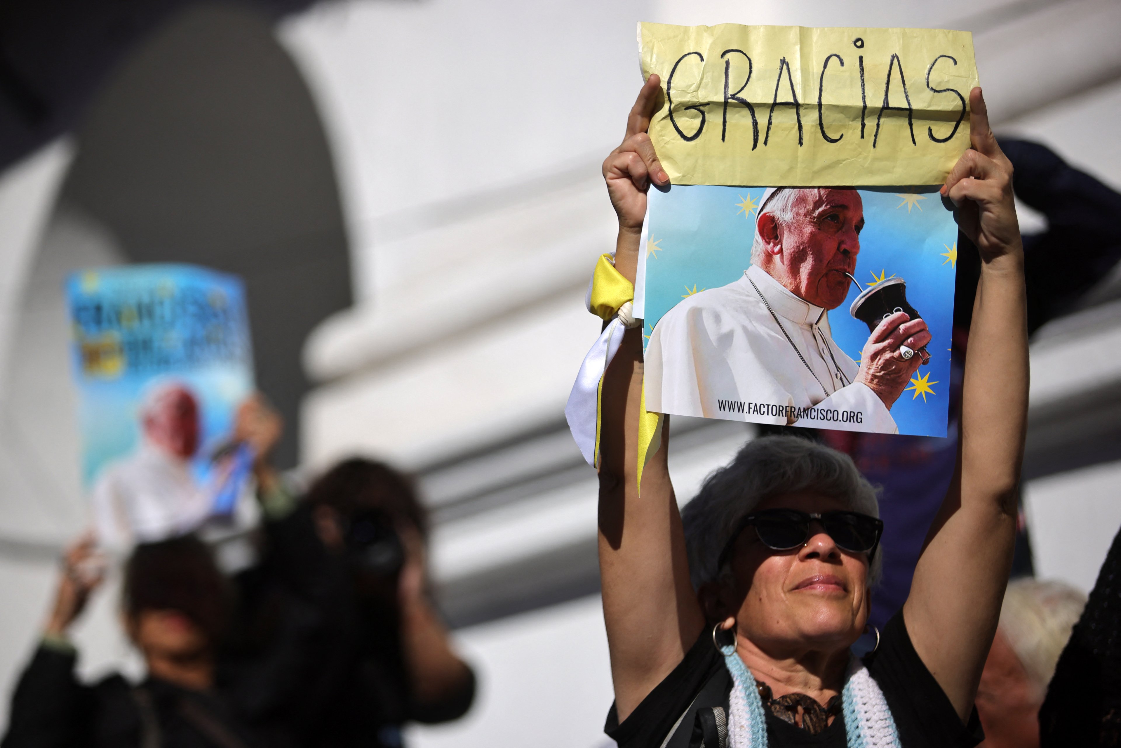 Uma mulher segura uma foto do Papa Francisco tomando mate com a inscrição "OBRIGADO" durante uma missa de despedida em frente à Catedral de Buenos Aires