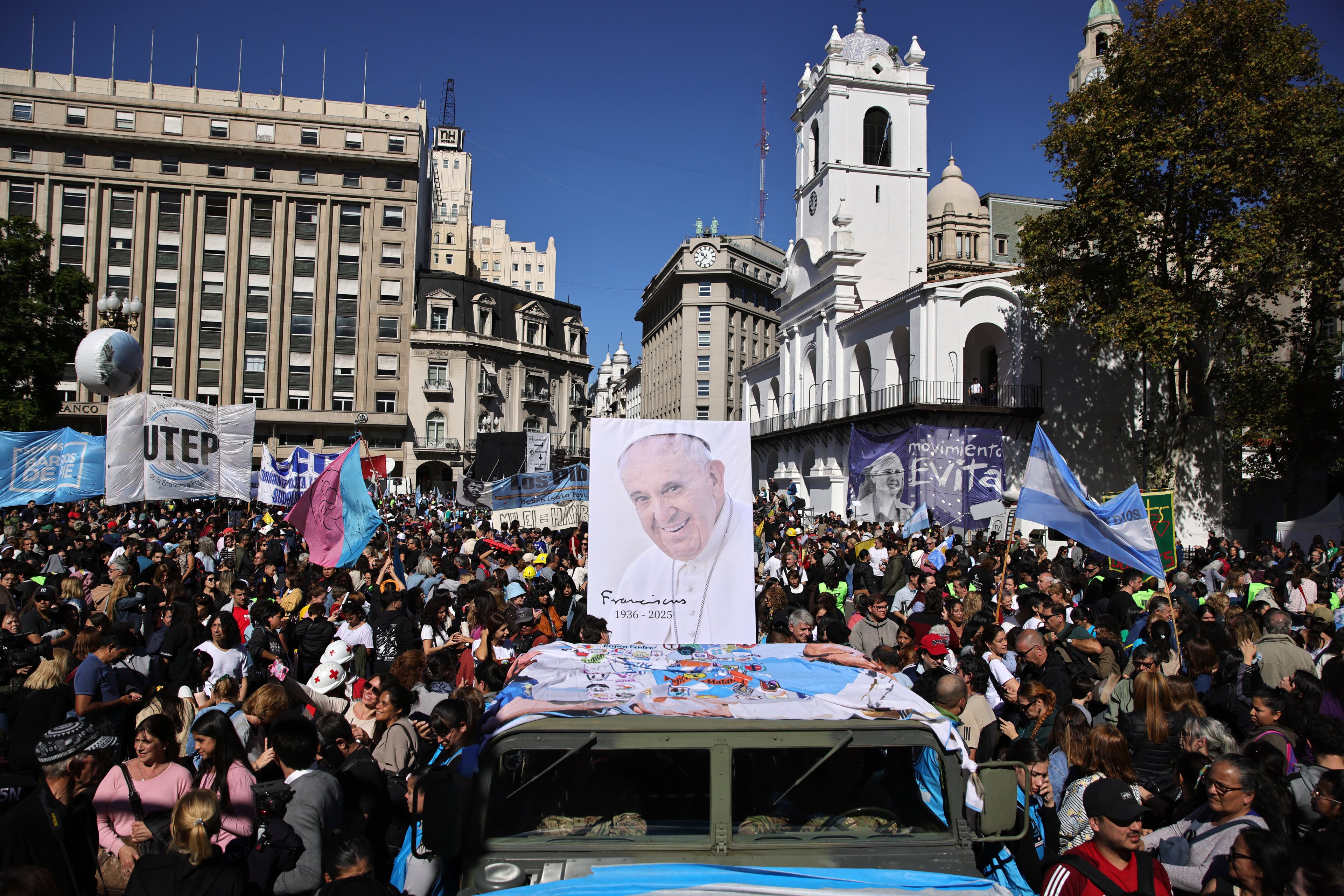 A military vehicle carries an image of Pope Francis during a pilgrimage through Buenos Aires on April 26, 2025, after a mass to bid him farewell. With songs, candles, flags, and prayers, Buenos Aires mourners marked the burial of pontiff and native son Pope Francis on Saturday. As the 88-year-old was being laid to rest an ocean away in Rome, thousands gathered by Buenos Aires' cathedral for dawn vigils and a mass of remembrance. (Photo by Emiliano Lasalvia / AFP)