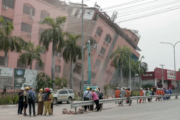 Rescue workers stand on the street next to a collapsed building in Mandalay on April 5, 2025, following the March 28 earthquake. The shallow 7.7-magnitude earthquake on March 28 flattened buildings across Myanmar, killing more than 3,000 people and making thousands more homeless. (Photo by Zaw Htun / AFP) (Zaw Htun/AFP)