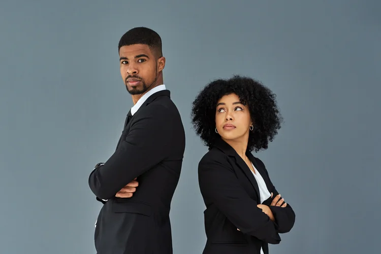 Shot of young businessman and businesswoman standing back to back against a grey studio background (	LaylaBird/Getty Images)
