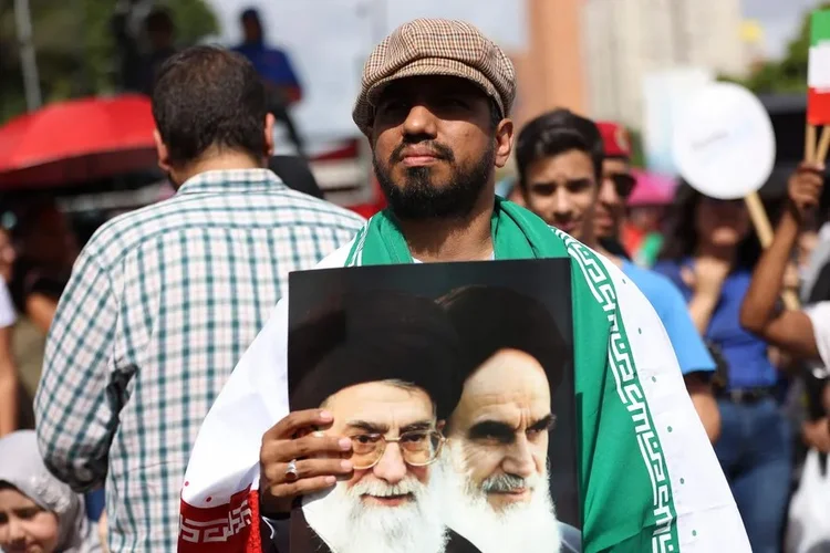Manifestante segura foto com as imagens do líder supremo do Irã, Ali Khamenei, e do fundador da República Islâmica, aiatolá Ruhollah Khomeini (Pedro MATTEY / AFP)