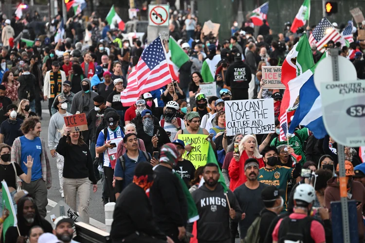 Demonstrators march in front of the Federal Building before curfew goes in effect following days of protests in response to federal immigration operations in Los Angeles on June 10, 2025. An overnight curfew went into effect in protest-hit downtown Los Angeles on June 10, with Mayor Karen Bass earlier saying it was to "stop the vandalism, to stop the looting" after several days of unrest.
Manifestantes protestam no centro de Los Angeles, na tarde de terça, 10 (Robyn Beck/AFP)