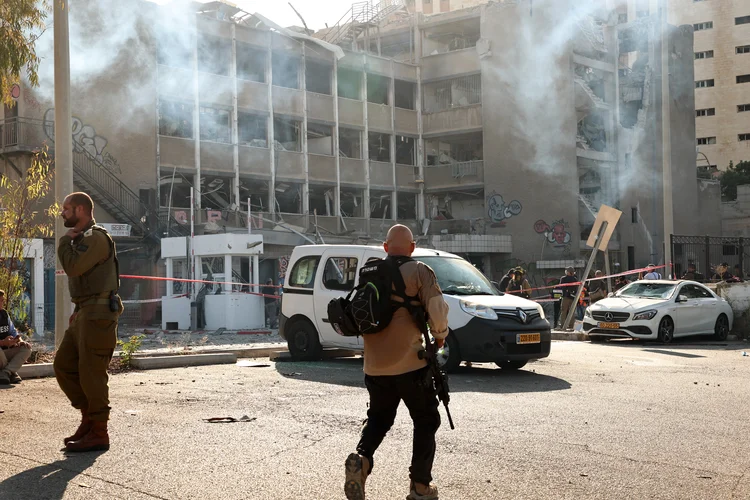 Members of the Israeli security forces walk as smoke emanates from a building reportedly hit by an Iranian strike in Haifa on June 20, 2025, amid the ongoing fire exchange between Israel and Iran. (Photo by Fadel SENNA / AFP) (Fadel SENNA/AFP)