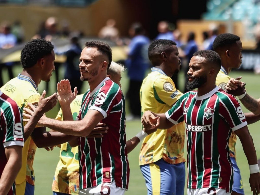 Jogadores do Fluminense e Sundowns FC se cumprimentando antes de partida no Mundial de Clubes da FIFA, com destaque para as camisas do Fluminense em verde, vermelho e branco e a torcida ao fundo no estádio.