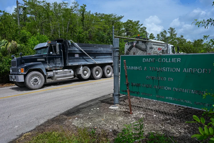 Caminhões deixam o Aeroporto de Transição e Treinamento Dade-Collier enquanto manifestantes protestam contra a construção de um centro de detenção de imigrantes, apelidado de "Alligator Alcatraz", nos Everglades (AFP)