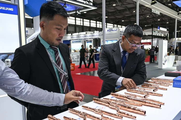 Visitantes verificam tubos de cobre em um estande durante a Feira Comercial Copper China 2025 ( Hector RETAMAL / AFP)