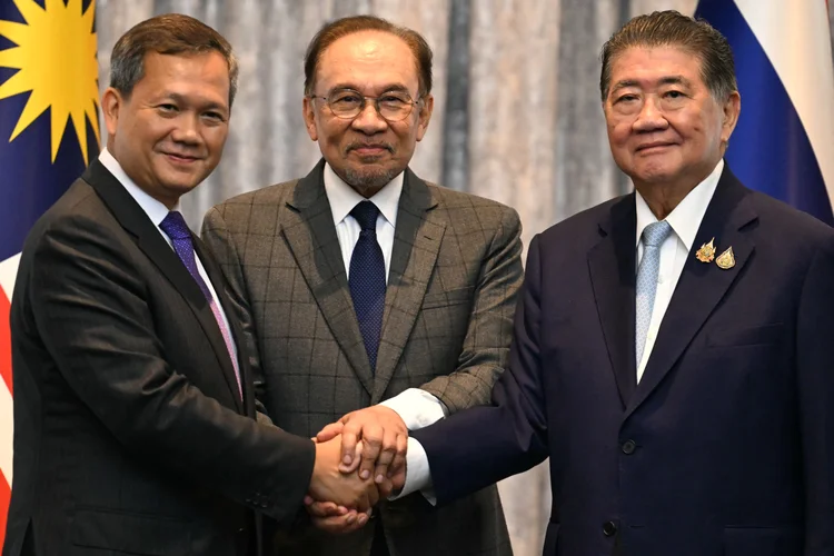 O primeiro-ministro da Malásia, Anwar Ibrahim, o primeiro-ministro do Camboja, Hun Manet, e o primeiro-ministro interino da Tailândia, Phumtham Wechayachai, posam para fotos enquanto apertam as mãos após uma coletiva de imprensa após as negociações sobre um possível cessar-fogo entre a Tailândia e o Camboja, em Putrajaya (MOHD RASFAN / POOL / AFP/Getty Images)