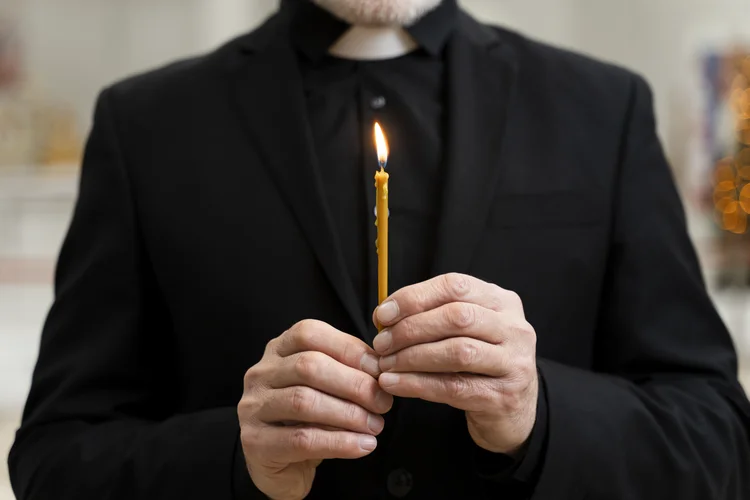Padre segurando uma vela (Fonte: Freepik)