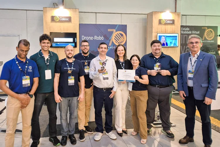 O técnico em Eletrotécnica da Celesc, Rafael Zimmermann Homma,(segundo da direita para a esquerda) , e o professor Rogério Sales Gonçalves, da Universidade Federal de Uberlândia (ao centro de camisa clara) (receberam o prêmio por desenvolverem um projeto que aplica inteligência artificial em drones-robôs para executar de forma autônoma atividades de manutenção em cabos de alta tensão (Celesc/Divulgação)