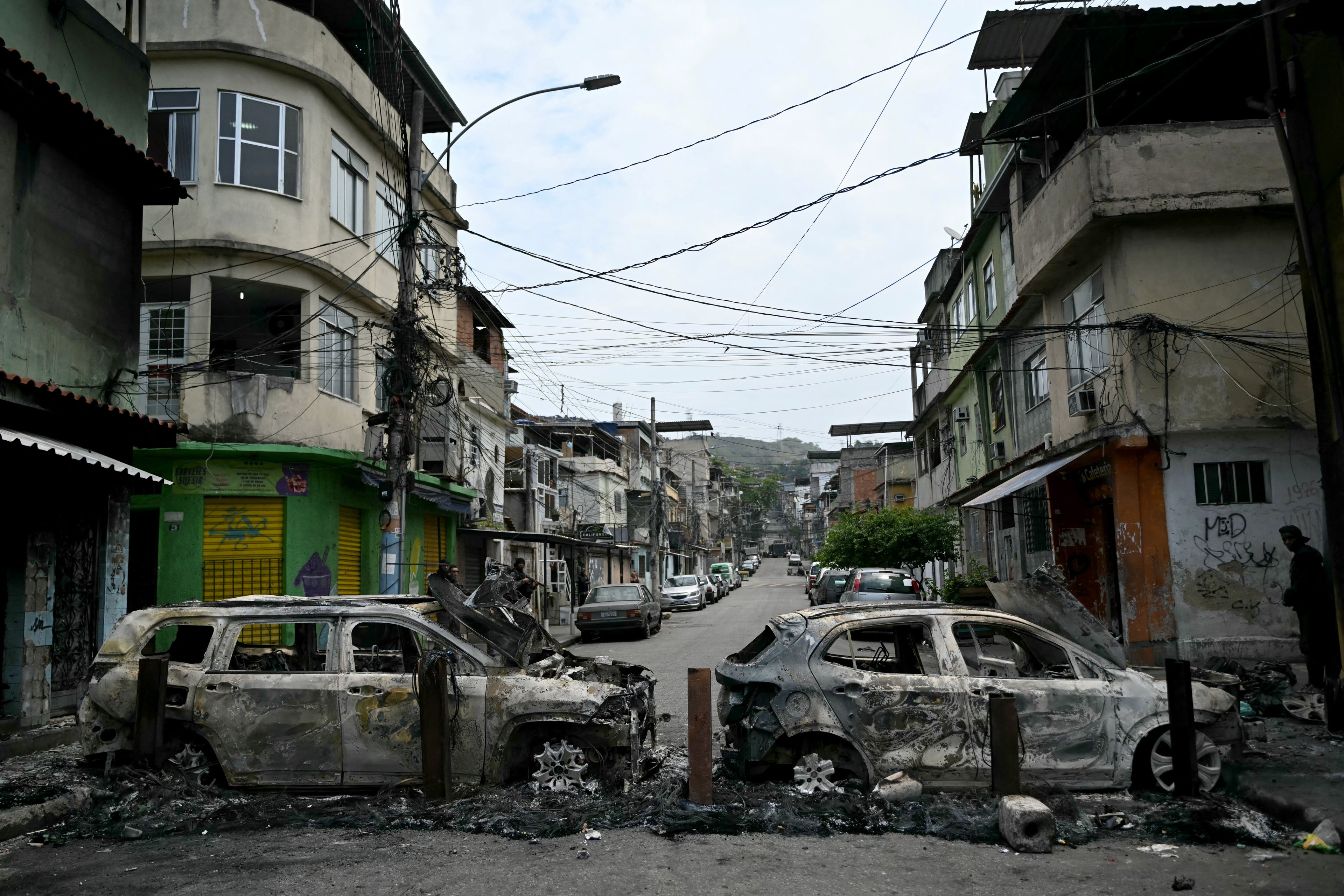 Um homem está ao lado de carros queimados durante uma barricada dentro da Operação Contenção na favela Vila Cruzeiro, no complexo da Penha, no Rio de Janeiro, nesta terça-feira, 28
