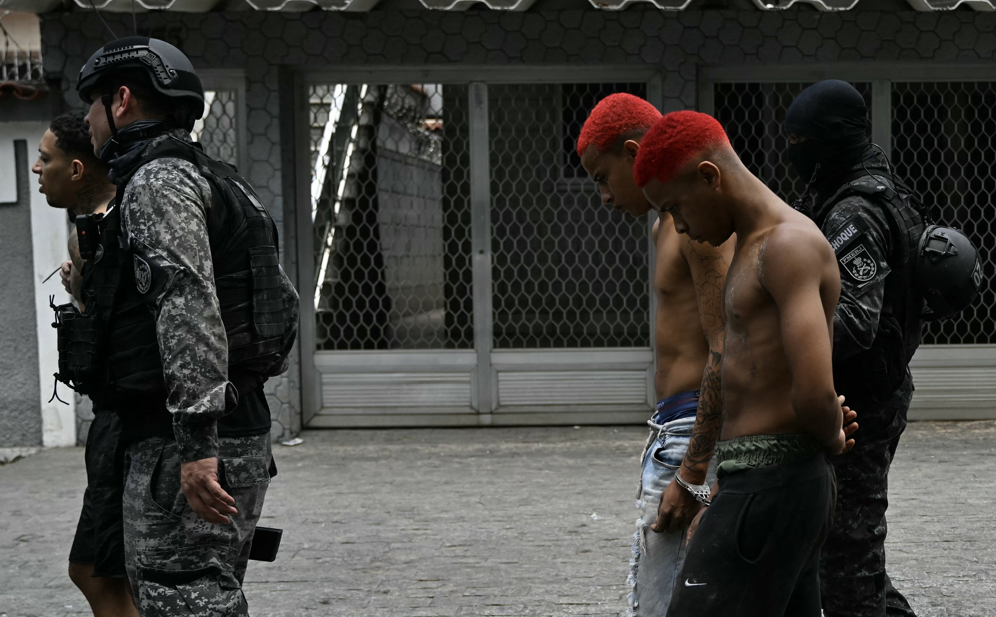 Policiais escoltam suspeitos presos durante a Operação Contenção para fora da favela Vila Cruzeiro, no complexo da Penha, no Rio de Janeiro, nesta terça-feira, 28