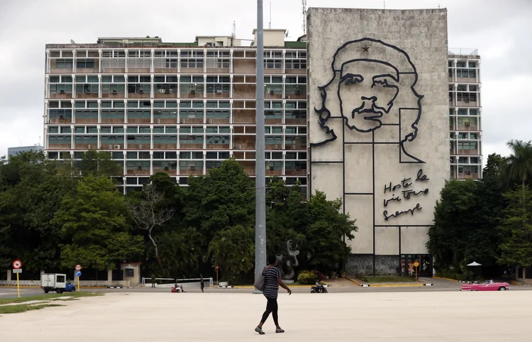 AME3863. LA HABANA (CUBA), 30/11/2025.- Una mujer camina frente al edificio del Ministerio del Interior de Cuba (Minint) con la imagen del guerrillero argentino-cubano Ernesto 'Ché' Guevara este viernes, en la plaza de la Revolución en La Habana (Cuba). La presión militar de Washington sobre Venezuela y la fijación con Cuba del secretario de Estado de EE.UU., Marco Rubio, preocupan sobremanera en La Habana, donde se analizan las derivadas políticas y sobre todo económicas de un potencial cambio de régimen en Caracas. EFE/ Ernesto Mastrascusa