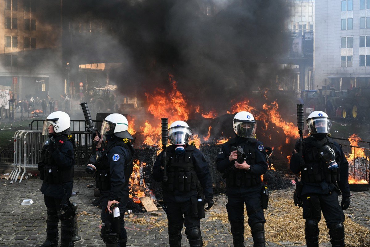 Fogo na praça: agentes da polícia evacuam a Praça de Luxemburgo, perto do Parlamento Europeu, durante um protesto de agricultores