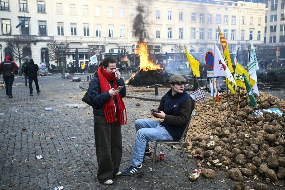 Bruxelas: agricultor senta-se numa cadeira ao lado de batatas perto do Parlamento Europeu, na Praça de Luxemburgo, durante um protesto de agricultores