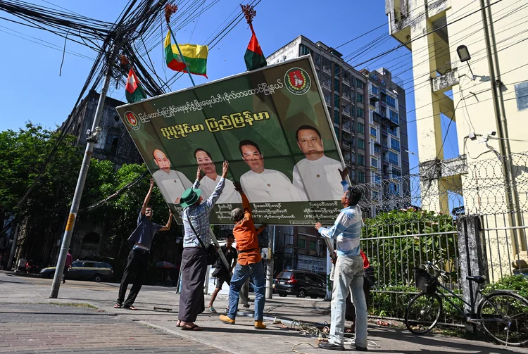 Homens retiram cartaz de campanha da rua na sexta, 26, antes da votação de domingo, em Yangon, Mianmar (Sai Aung Main/AFP)